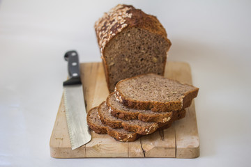 Brotlaib (Dinkelbrot) auf Holzbrett mit Messer, freigestellt