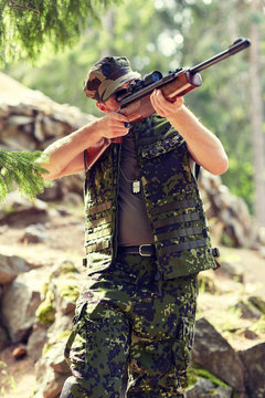 soldier or hunter shooting with gun in forest