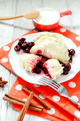 traditional Ukrainian and Russian cuisine , sweet dumplings called varenyky of dough with cherry, sour cream and cinnamon in a clay plate on a white wooden background