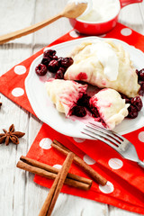 traditional Ukrainian and Russian cuisine , sweet dumplings called varenyky of dough with cherry, sour cream and cinnamon in a clay plate on a white wooden background