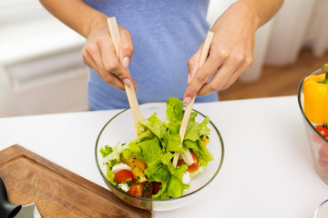 close up of woman cooking vegetable salad at home