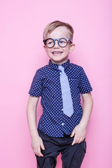 Little adorable kid in tie and glasses. School. Preschool. Fashion. Studio portrait over pink...