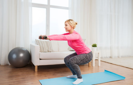 Smiling Woman With Dumbbells Exercising At Home