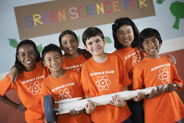 Students in the Science Club standing under the sign Green Science Fair, holding a long rocket, 