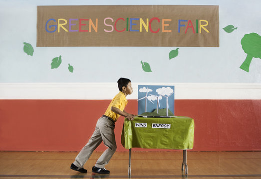 A boy pushing a table into a room at the Green Science Fair, 