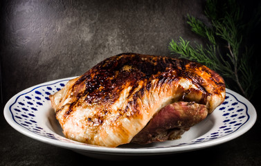 roasted pork ham in a dish on dark flat stone ambient 