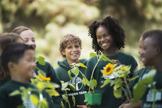 Children in a group learning about plants and flowers, carrying plants and sunflowers, 