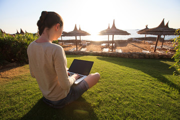 businesswoman typing on her laptop with sunflare on the resort