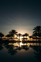 Fototapeta na wymiar Beautiful sunset at a beach resort in tropics with palms and wat