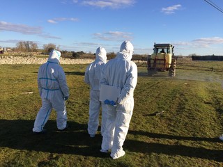 agricultores con trajes de proteccion sulfatando el campo