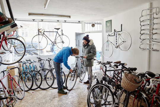 Two young men in a cycle shop, talking,