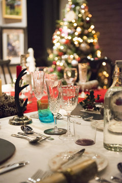 A table laid for a Christmas meal, with silver and crystal glasses and a Christmas tree in the background, 