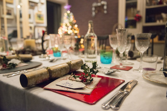 A table laid for a Christmas meal, with silver and crystal glasses and a Christmas tree in the background, 
