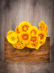 Bouquet of gerber flowers in the box on wooden background