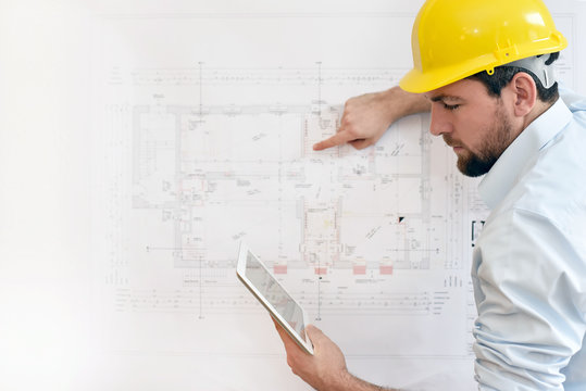 Bauingenieur mit Tablet vor technischer Zeichnung beim Hausbau // engineer with Tablet and technical drawing in house construction