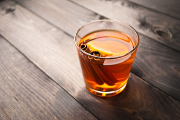 Lemon slice and cinnamon sticks in a cup of black tea on wooden rustic background