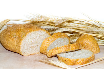 whole grain bread, slices of bread and ears of wheat on wooden table with white background