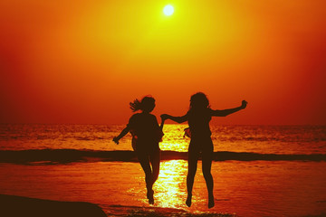 Fototapeta premium Happy Girls Jumping in Sea Sunset. Silhouette. Thailand.
