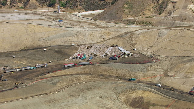 Aerial shot of trucks and tractors working in landfill