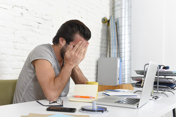 worried student or businessman at computer covering his face with his hands depressed and sad