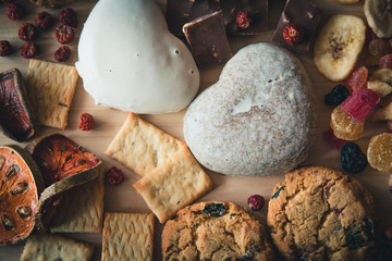 Gingerbread heart-shaped biscuits and a handmade chocolate. On the background of dried fruits and chocolate on wooden background