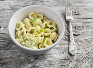 Delicious healthy vegetarian pasta with broccoli and pine nuts pesto in ceramic bowl on light...