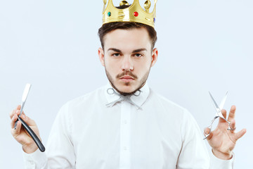 Young barber posing with razor and scissors in his hands
