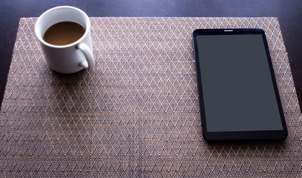 Coffee cup and tablet pc on kitchen table 