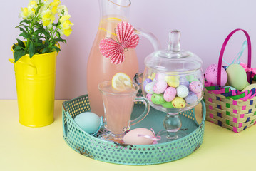 Metal tray with pink lemonade pitcher, glass and jar with chocolate egg candies.