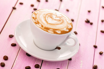 cup of cappuccino with heart foam, coffee beans on pink wooden background, drink hot product photography 