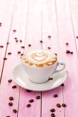 cup of cappuccino with heart foam, coffee beans on pink wooden background, drink hot product photography 