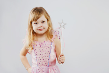 Lovely little girl posing with magic stick in studio