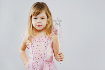 Little blond girl posing with silver magic stick in studio