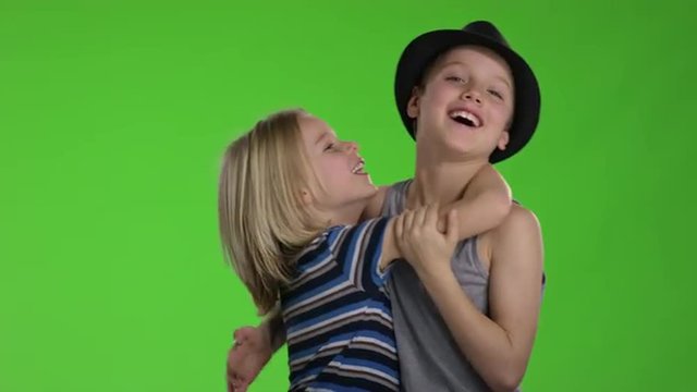 Two childs hugging each other and having fun in front of greenscreen