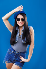 Young smiling woman posing on blue background, in studio