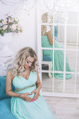 Beautiful young pregnant woman in fashionable dress in a interio