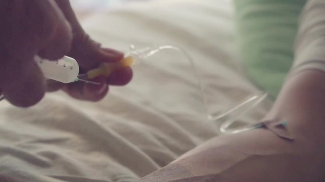 Hand of a patient with pulse meter lying with drop counter on the bed. Doctor fills medicine dropper syringe. 1920x1080
