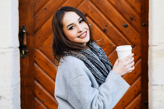 Cheerful young girl, holding cup of coffee in her hand