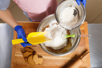 Confectioner holding yellow scoop, and cooking in the kitchen