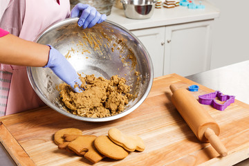 Young confectioner knead the dough in metallic bowl