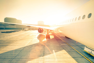 Generic airplane on terminal gate ready for takeoff - Modern international airport at sunset -...