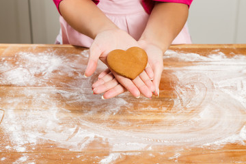 Young woman holding gingerbread in her hand in the kitchen