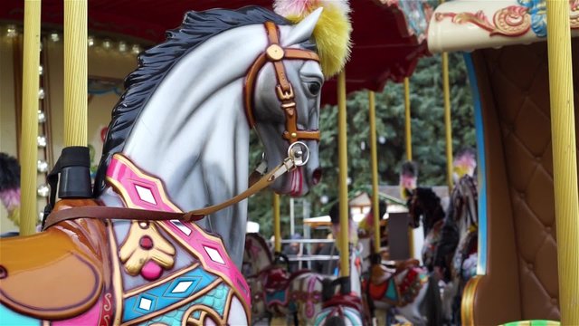 People having fun at amusement park, closeup of merry-go-round carousel horse
