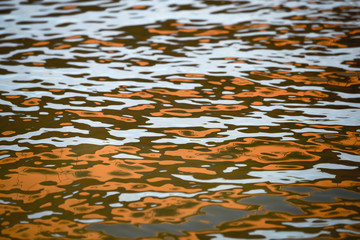 Orange blue white reflection on surface water with waves