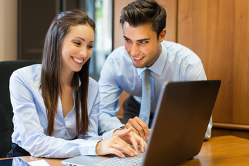 Smiling business people using a laptop computer in their office.