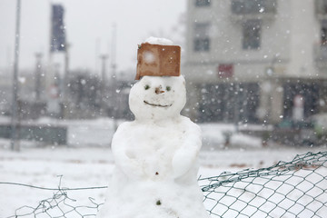Funny snowman in the park with cap made of cardboard