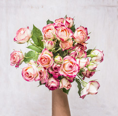 bouquet of pink shrub roses in the hand of the girl gift on March 8 on wooden rustic background top view