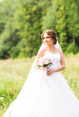 Fototapeta na wymiar Beautiful bride girl in wedding dress and bouquet of flowers, outdoors portrait