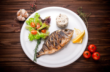 Fresh prepared dorado or sea bream fish with lemon, herbs on woo