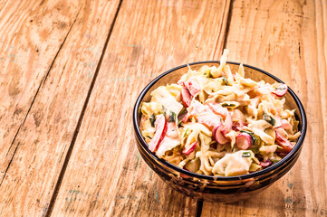 Vegetable salad with mayonnaise in bowl on wood background